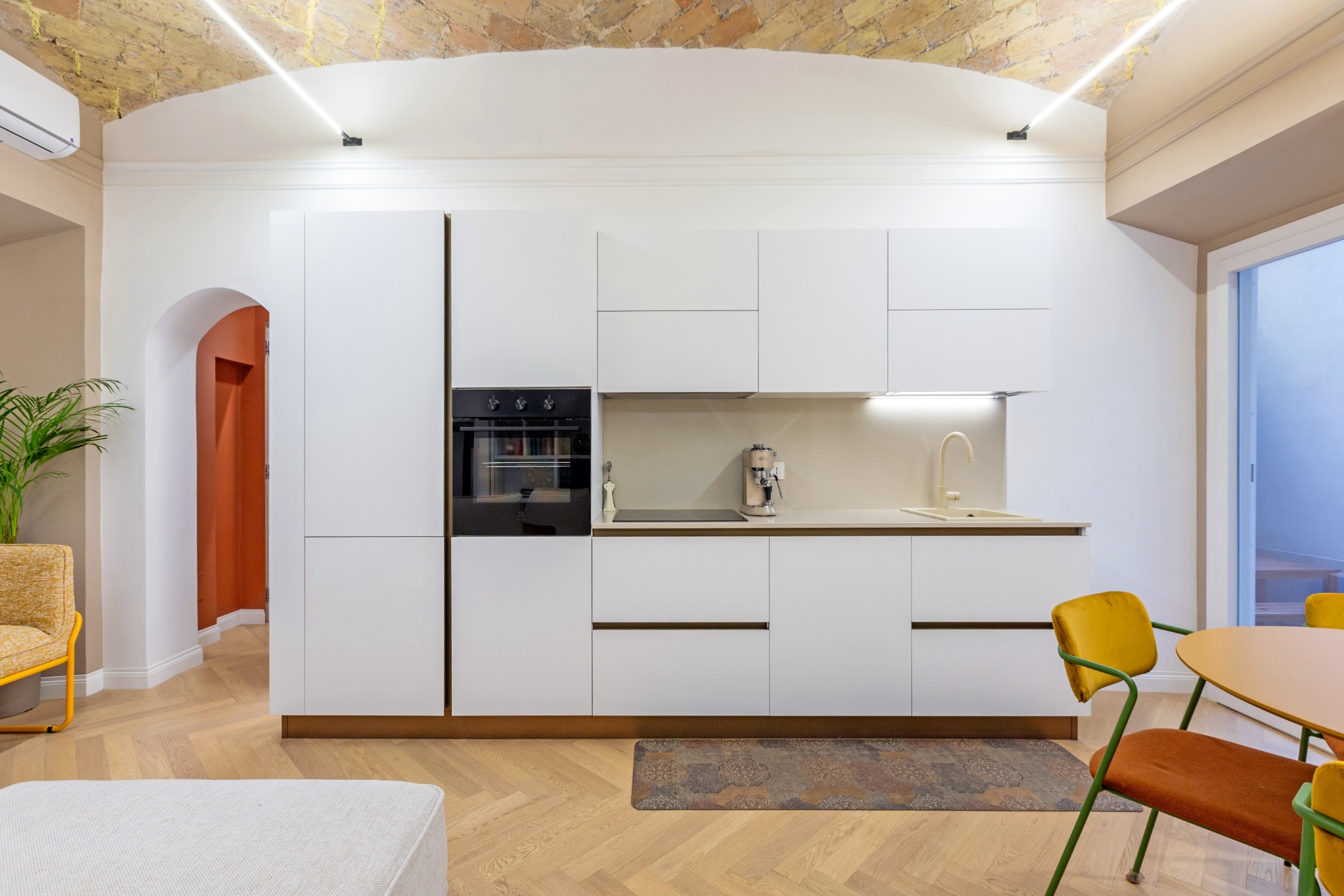 Cucina contemporanea bianca sotto il soffitto storico a volta