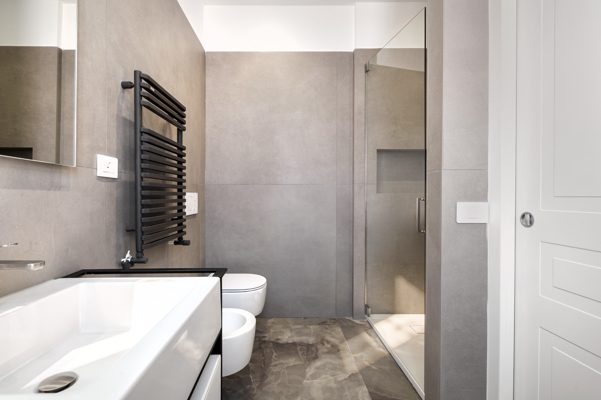 Vista del bagno con doccia in vetro e rivestimenti materici