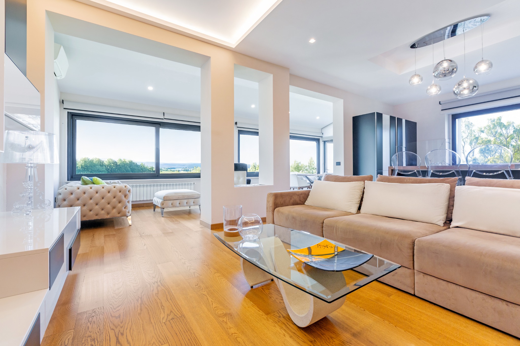 Living con divano, parquet e vetrate sul verde
