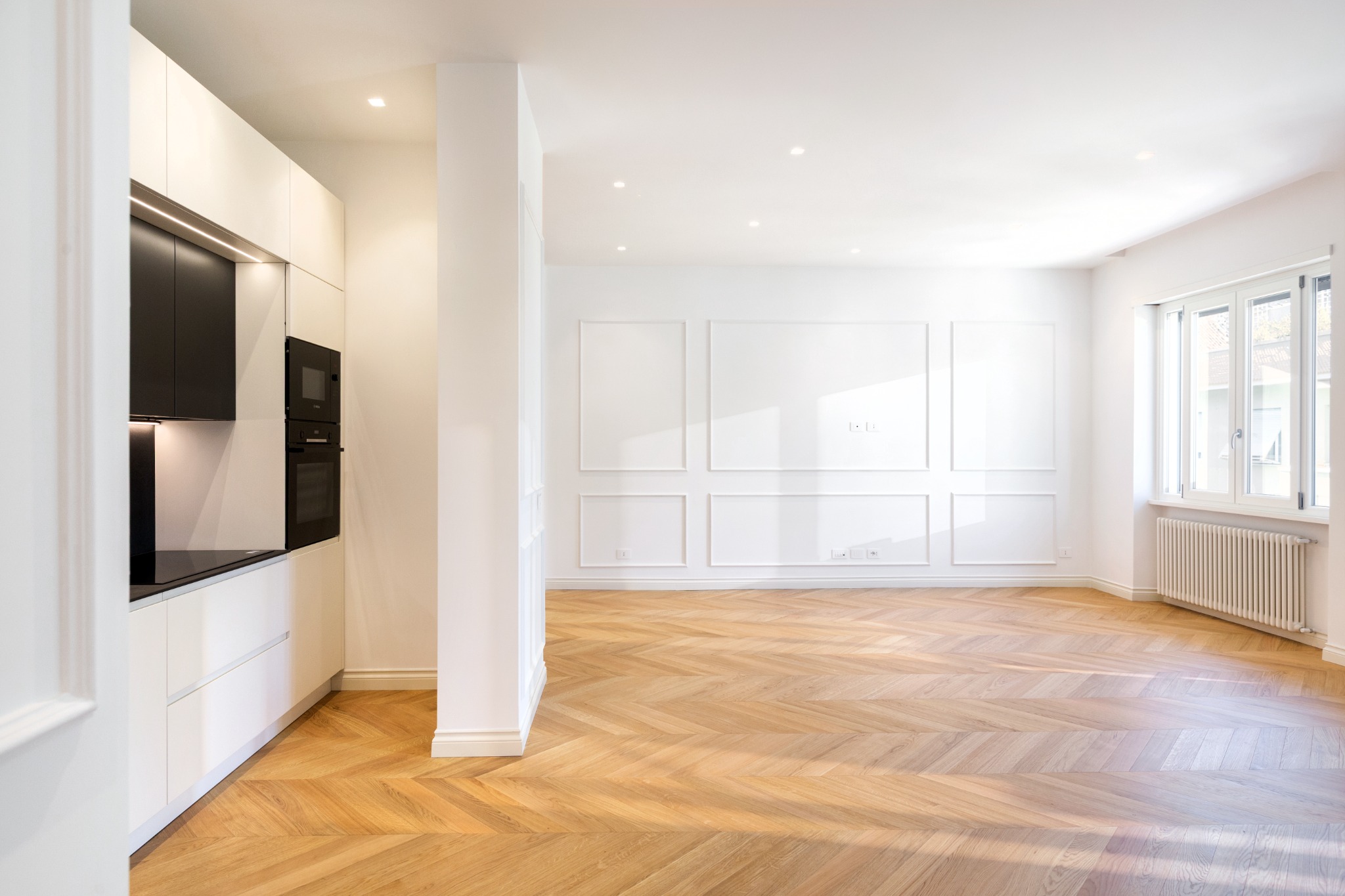 Dialogo tra cucina, boiserie e parquet nella zona giorno